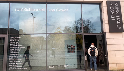 A person enters a building with a large glass facade.