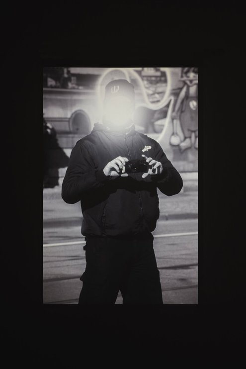 A black-and-white photograph. The person's face is blurred.